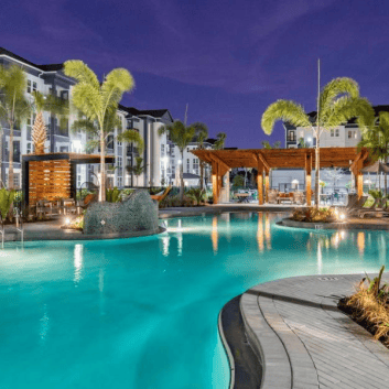 Twilight poolside oasis at NIKA's MacDill AFB per diem lodging, featuring illuminated luxury amenities and palm trees.